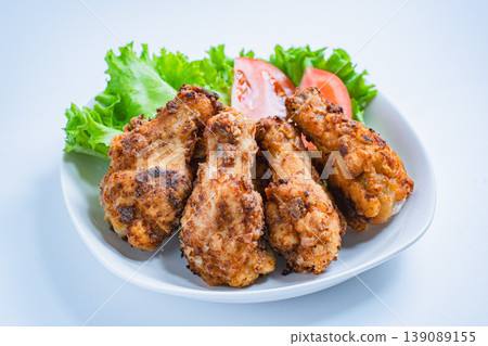 Deep-fried chicken wings with lettuce and tomato as a side dish, served on a white plate – a home-style meal. Deep-fried chicken wings with lettuce and tomato as a side dish, served on a white plate – a home-style meal. 139089155