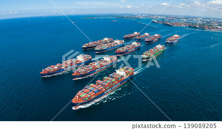 Container ships navigate through busy shipping lanes in ocean waters during daylight hours near a coastal city 139089205