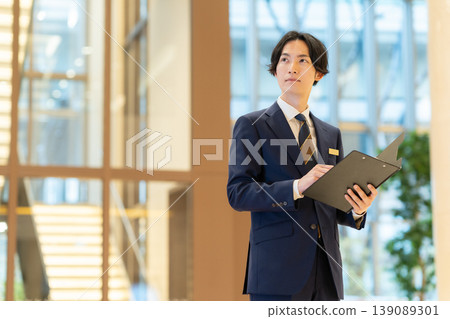 A male concierge working at a hotel. Filming assistance provided by: Denpa Gakuen Educational Foundation, Tokyo Electronics College. A male concierge working at a hotel. Filming assistance provided by: Denpa Gakuen Educational Foundation, Tokyo Electronics College. 139089301