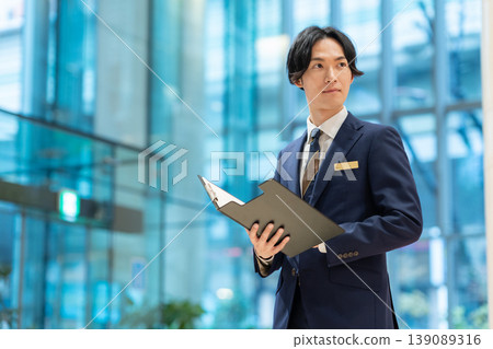 A male concierge working at a hotel. Filming assistance provided by: Denpa Gakuen Educational Foundation, Tokyo Electronics College. A male concierge working at a hotel. Filming assistance provided by: Denpa Gakuen Educational Foundation, Tokyo Electronics College. 139089316