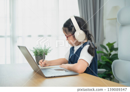 Young Girl Engaged in Online Learning at Home with Laptop and Headphones, Focusing on Education and Study Environment, Natural Light Young Girl Engaged in Online Learning at Home with Laptop and Headphones, Focusing on Education and Study Environment, Natural Light 139089347