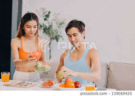 A happy couple prepares fresh vegetables, laughing and enjoying cooking a healthy meal together. A happy couple prepares fresh vegetables, laughing and enjoying cooking a healthy meal together. 139089420