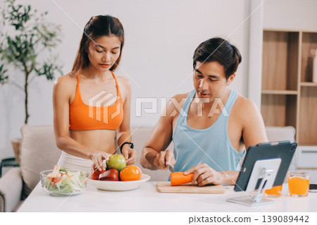 A happy couple prepares fresh vegetables, laughing and enjoying cooking a healthy meal together. A happy couple prepares fresh vegetables, laughing and enjoying cooking a healthy meal together. 139089442