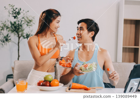 A happy couple prepares fresh vegetables, laughing and enjoying cooking a healthy meal together. A happy couple prepares fresh vegetables, laughing and enjoying cooking a healthy meal together. 139089449