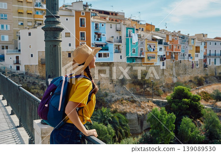 Travel concept. Traveler in a straw hat looking at the beautiful city of Villajoyosa with colorful beautiful houses and buildings 139089530