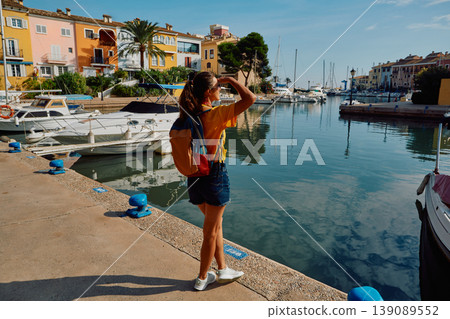 Woman traveler stands on pier with yachts and boats at beautiful harbor of Port Saplaya near Valencia with colorful houses. Traveler concept Woman traveler stands on pier with yachts and boats at beautiful harbor of Port Saplaya near Valencia with colorful houses. Traveler concept 139089552