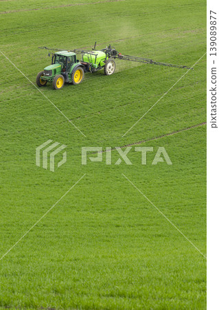 Agricultural tractor spraying green crop field in Czechia Agricultural tractor spraying green crop field in Czechia 139089877