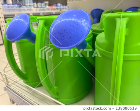Bright green watering cans with blue nozzles displayed in a store aisle Bright green watering cans with blue nozzles displayed in a store aisle 139090539