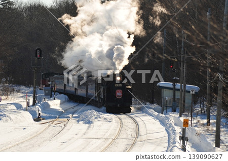 A steam locomotive running through wintery Hokkaido: a railway scene of white smoke and snowy landscape. 139090627
