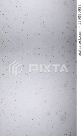 Minimalist texture of snowflakes falling against a gray sky. Winter background with soft bokeh and light snow flurry. Abstract seasonal concept of cold weather and frost. Snow vertical 139090988