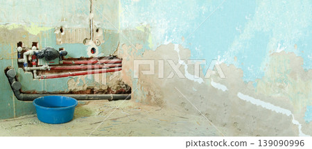 Bathroom renovation process with exposed water pipes and old blue wall. Home repair concept showing plumbing installation, damaged plaster, and messy construction site 139090996