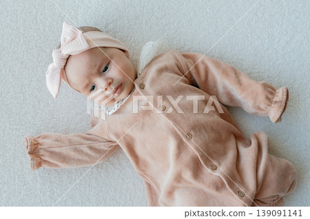 Baby girl lying on soft background in pastel outfit. Calm and minimal composition for parenting and lifestyle use. Baby girl lying on soft background in pastel outfit. Calm and minimal composition for parenting and lifestyle use. 139091141