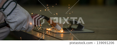Close-up of hands working in metalworking with arc welding, where sparks fly, in a manufacturing plant. Industrial technology background material. 139091206