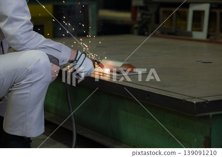 Close-up of hands working in metalworking with arc welding, where sparks fly, in a manufacturing plant. Industrial technology background material. 139091210