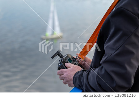 An elderly man control a model Boat Moving Across Lake - Recreational Hobby Concept An elderly man control a model Boat Moving Across Lake - Recreational Hobby Concept 139091216