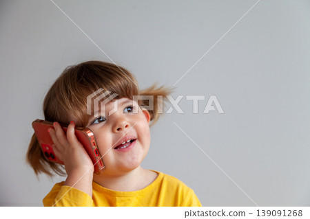 Preschooler interacting with her smartphone, depicting cyber safety and digital learning. 139091268
