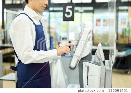 Male cashier entering data into the register Male cashier entering data into the register 139091401