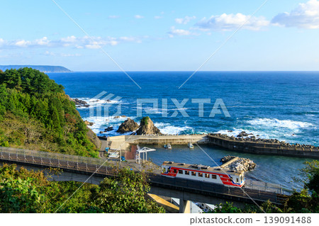 A Sanriku Railway diesel train crosses the Osawa Bridge with the deep blue Pacific Ocean as a backdrop. 139091488
