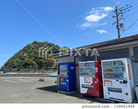 Three vending machines and a view of a small hill in the harbor. Three vending machines and a view of a small hill in the harbor. 139091494