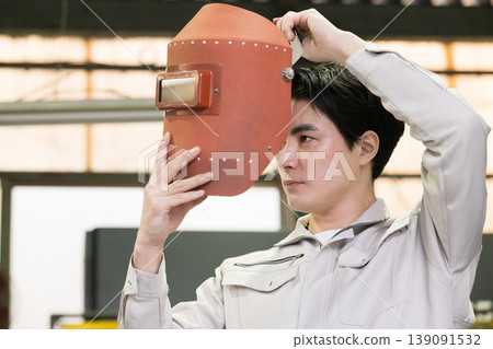 A worker wearing a welding mask – an image of a craftsman or welder at a manufacturing site. Stay safe today! 139091532