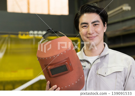A worker wearing a welding mask – an image of a craftsman or welder at a manufacturing site. Stay safe today! 139091533