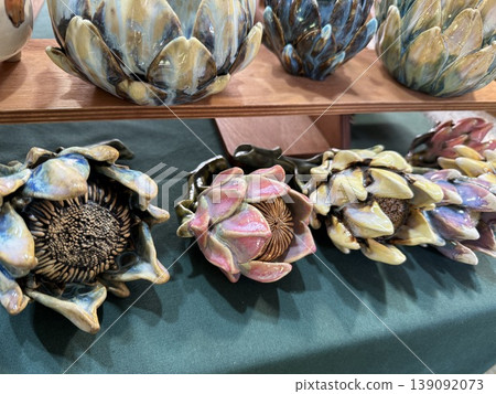 Ceramic artichoke sculptures on wooden shelf with artistic display and textured ceramic detail Ceramic artichoke sculptures on wooden shelf with artistic display and textured ceramic detail 139092073