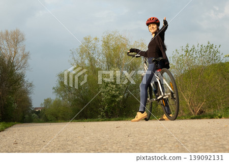 Happy woman cyclist showing thumbs up gesture while riding Happy woman cyclist showing thumbs up gesture while riding 139092131