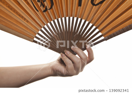 Elegant Hand Holding Decorative Fan on White. Woman Hand with Folding Fan Isolated Studio Shot. 139092341