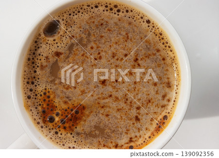 Macro top view of coffee crema texture in cup on white background.Selective focus. Copy space Macro top view of coffee crema texture in cup on white background.Selective focus. Copy space 139092356