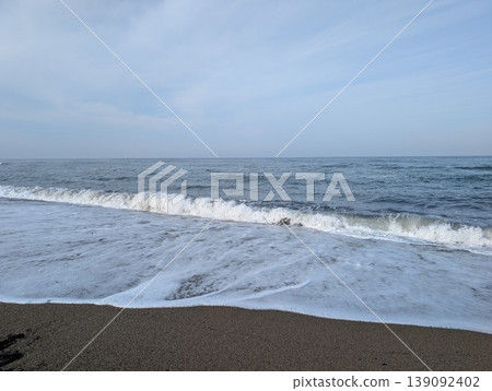 Waves crashing onto the sandy beach, with dynamic ocean spray as a backdrop. 139092402