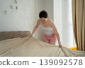 A caucasian woman made her bed in her bedroom on a sunny day. morning routine 139092578