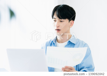 A young man thinking while looking at documents. A young man thinking while looking at documents. 139092842