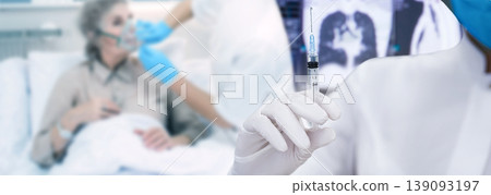Vaccination of the coronavirus.Doctor holding a syringe with a vaccine, over a patient with pneumonia on artificial lung ventilation. 139093197
