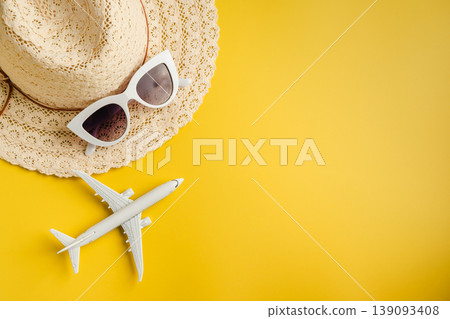 Travel-themed flat lay, summer holiday background. Toy model airplane, sunglasses, sun hat over yellow backgrounds, copy space Travel-themed flat lay, summer holiday background. Toy model airplane, sunglasses, sun hat over yellow backgrounds, copy space 139093408