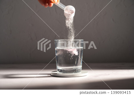 Pouring food supplement powder in glass of water. Collagen, protein powder, vitamins. Pouring food supplement powder in glass of water. Collagen, protein powder, vitamins. 139093415