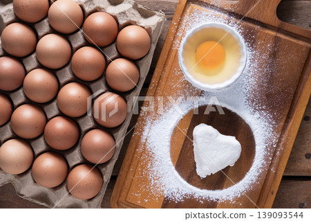 Fresh Eggs and White heart-shaped dough Ingredients on Rustic Wooden Table 139093544