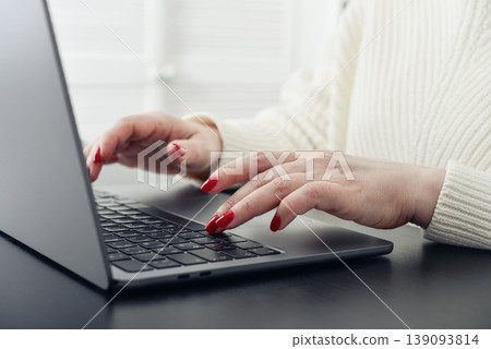 Close up of female hands with red manicure typing on a laptop keyboard. Close up of female hands with red manicure typing on a laptop keyboard. 139093814