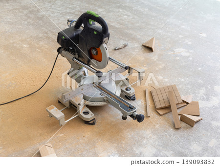 Table saw and oak parquet plank pieces on floor during wood floor installation. Home construction Table saw and oak parquet plank pieces on floor during wood floor installation. Home construction 139093832
