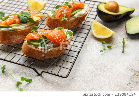 Salmon avocado toasts with microgreens and sesame seeds 139094154