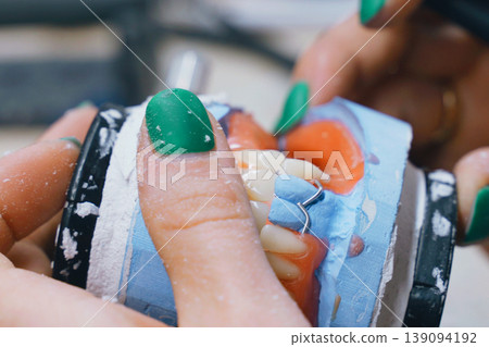Tech checks bite alignment on a denture model during work 139094192
