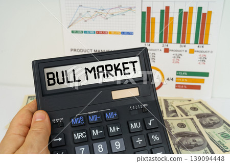 On the table there are financial reports, dollars, in the hands of a calculator with the inscription - bull market On the table there are financial reports, dollars, in the hands of a calculator with the inscription - bull market 139094448