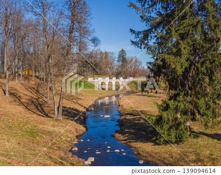 Stone bridge arches gracefully over a quiet stream Stone bridge arches gracefully over a quiet stream 139094614