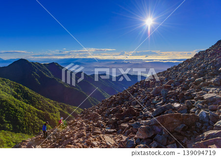 A sea of clouds and sunrise viewed from the climb up Mt. Jonen in the Northern Alps; the shining morning sun and the mountain range. 139094719