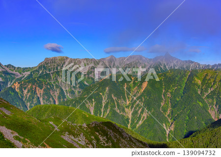 A panoramic view of the Hotaka mountain range from Mt. Jonen in the Northern Alps, showcasing rugged rock faces and majestic peaks shining in the morning sun. A panoramic view of the Hotaka mountain range from Mt. Jonen in the Northern Alps, showcasing rugged rock faces and majestic peaks shining in the morning sun. 139094732