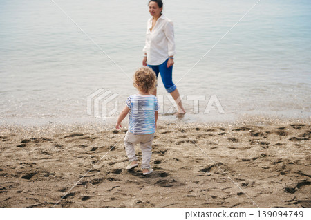 Mother and Toddler Walking on Sandy Beach Together at Calm Seaside Shore 139094749