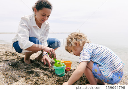 Mother And Toddler Playing Together On Beach With Sand Toys Mother And Toddler Playing Together On Beach With Sand Toys 139094796