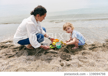 Mother and Toddler Playing With Sand Toys on a Calm Seaside Beach Together 139094798