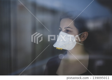 A woman staying at home in quarantine and watching the outside world through the window A woman staying at home in quarantine and watching the outside world through the window 139095011