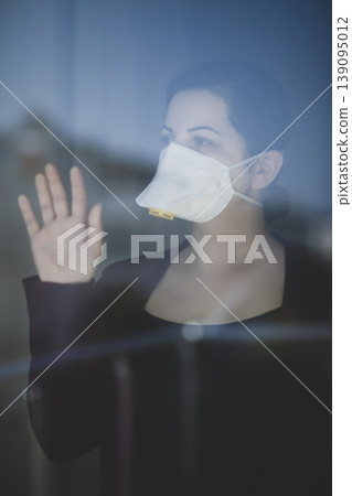 A woman staying at home in quarantine and watching the outside world through the window A woman staying at home in quarantine and watching the outside world through the window 139095012
