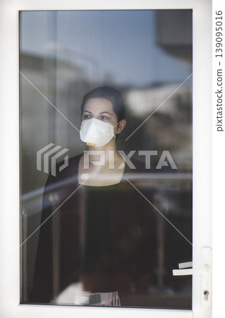 A woman staying at home in quarantine and watching the outside world through the window A woman staying at home in quarantine and watching the outside world through the window 139095016